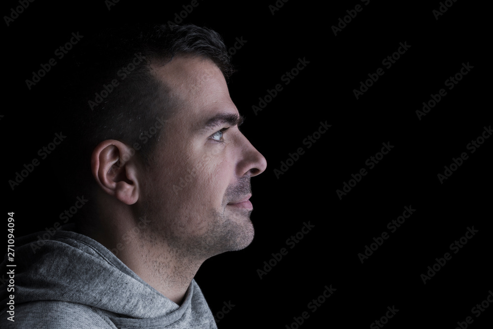 Side studio portrait of a serious man looking sideways. Isolated on black background. Horizontal. Copyspace. Side studio portrait of a serious man looking sideways. Isolated on black background. Horizontal. Copyspace.