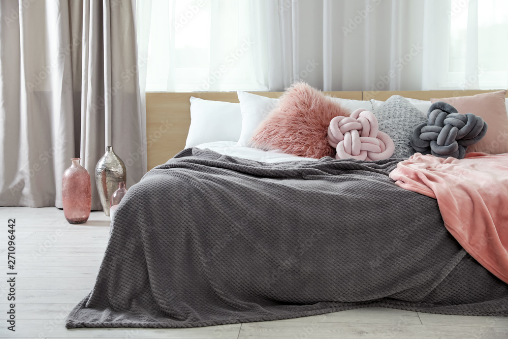 Comfortable bed with pillows and plaid in modern room interior Comfortable bed with pillows and plaid in modern room interior