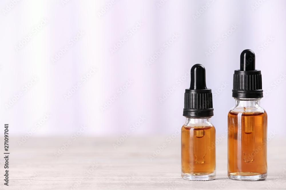 Bottles of essential oils on table against light background, space for text. Cosmetic products Bottles of essential oils on table against light background, space for text. Cosmetic products
