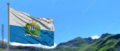 San Marino flag waving in the blue sky with green fields at mountain peak background. Nature theme.