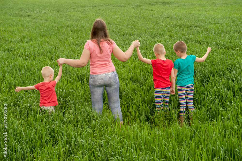 Happy mother with children playing on a green field with wheat..Unity with nature concept Happy mother with children playing on a green field with wheat..Unity with nature concept