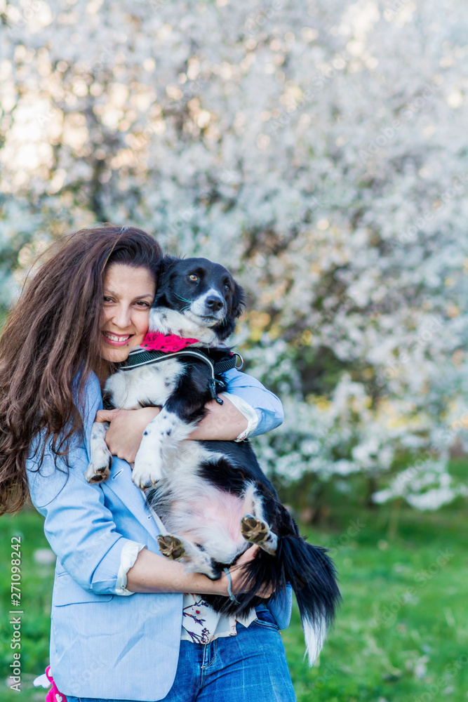 Beautiful Smiling Woman Hugging  Her Cute  Dog in a Spring Garden .Pet and Owner Outdoor in the Spring