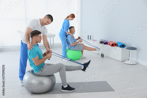 Professional physiotherapists working with patients in rehabilitation center photo