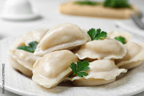 Tasty dumplings served with parsley on plate, closeup