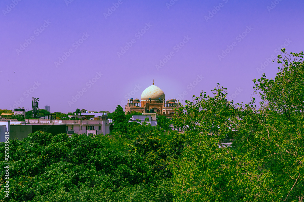 Humayun's tomb surrounded by green trees in New Delhi, India at midday. Distant view on the famous building in the Indian capital.