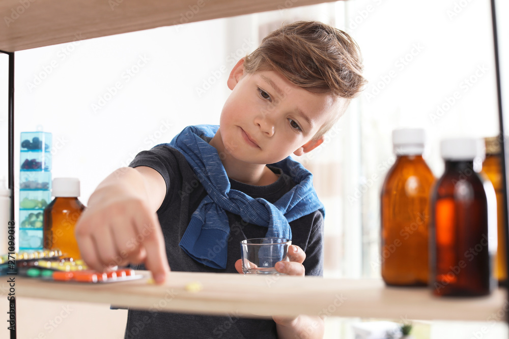 Little child taking pills from shelf at home. Danger of medicament intoxication Little child taking pills from shelf at home. Danger of medicament intoxication