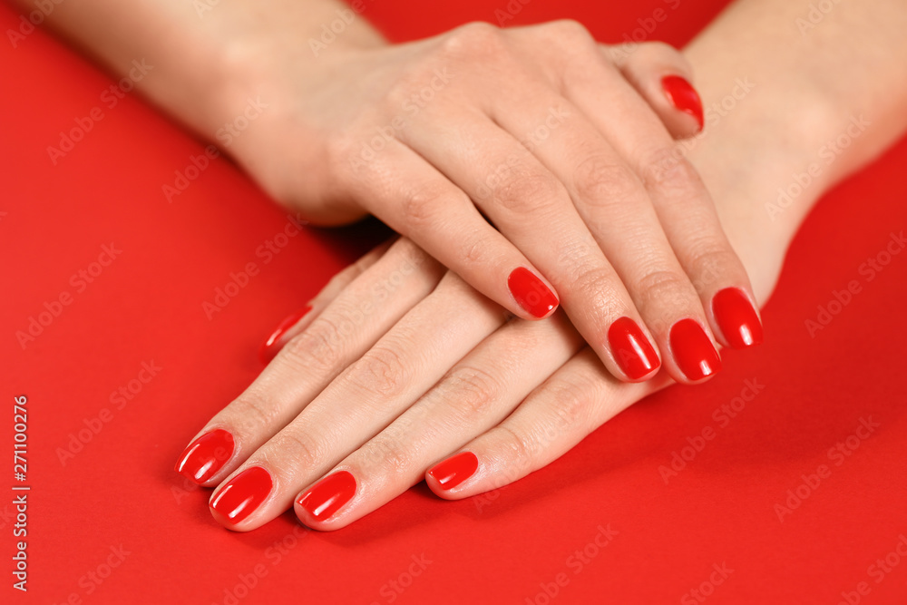 Woman showing manicured hands with red nail polish on color background, closeup