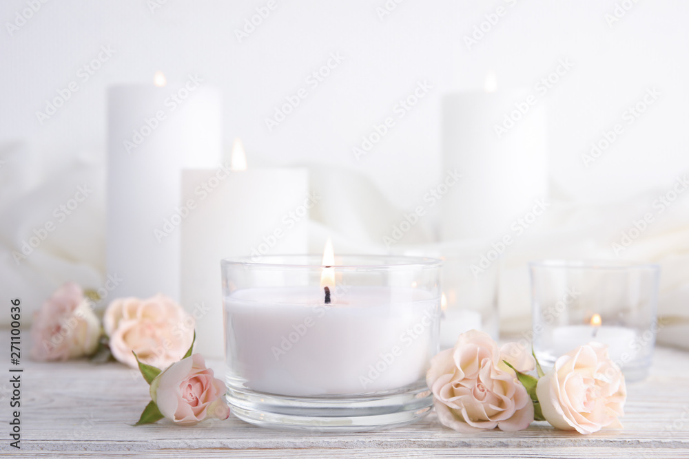 Composition with burning aromatic candle and roses on wooden table Composition with burning aromatic candle and roses on wooden table