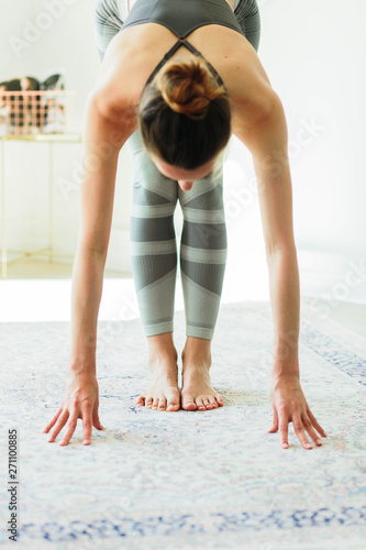 Young attractive smiling woman practicing yoga in a bright room