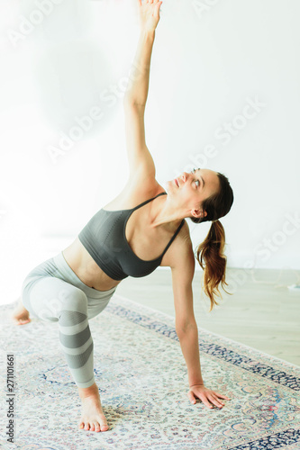 Young attractive smiling woman practicing yoga in a bright room photo