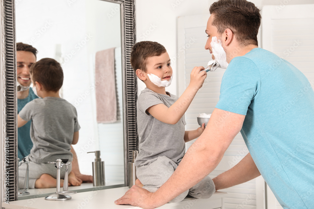 Obraz premium Little son applying shaving foam onto dad's face in bathroom