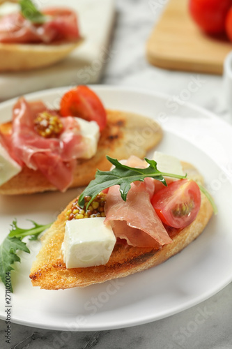 Plate of tasty bruschettas with prosciutto on table