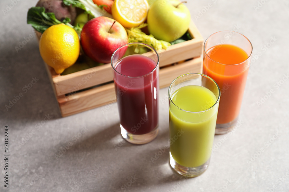 Glasses of different juices and wooden crate with fresh ingredients on table Glasses of different juices and wooden crate with fresh ingredients on table