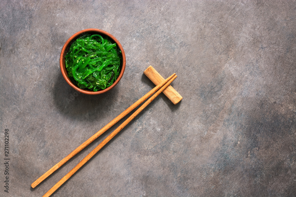 Wakame Chuka or seaweed salad with sesame seeds in bowl on dark brown rustic background. Traditional Japanese food. Top view, flat lay,copy space. Wakame Chuka or seaweed salad with sesame seeds in bowl on dark brown rustic background. Traditional Japanese food. Top view, flat lay,copy space.