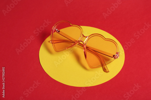 Stylish heart shaped glasses on color background