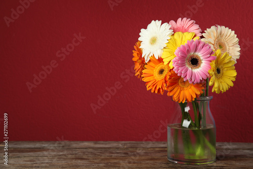 Wallpaper Mural Bouquet of beautiful bright gerbera flowers in vase on wooden table against color background. Space for text Torontodigital.ca