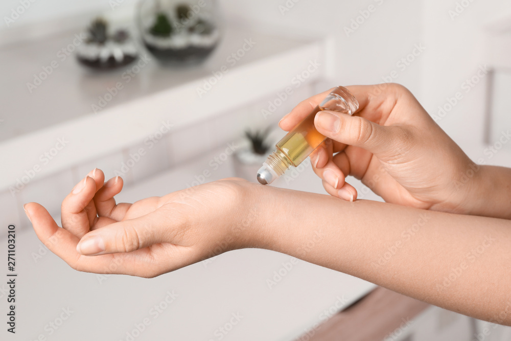 Woman applying essential oil on wrist indoors, closeup - obrazy, fototapety, plakaty 