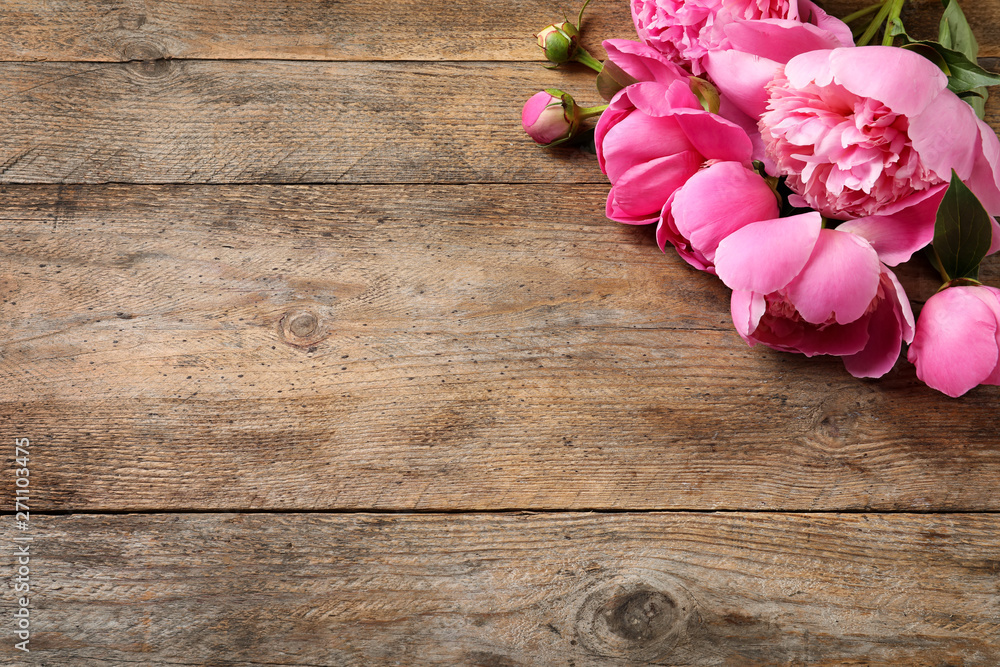 Fragrant peonies on wooden table, top view with space for text. Beautiful spring flowers
