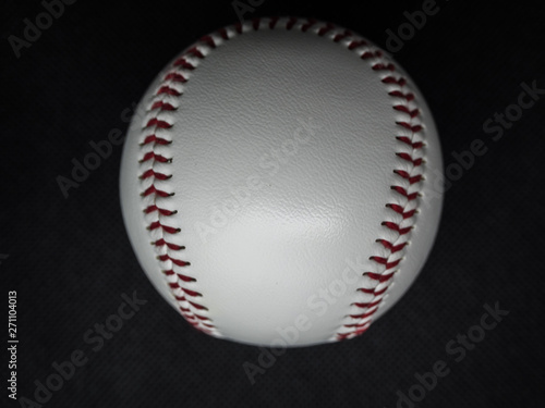 Baseball ball with red threads on a dark background