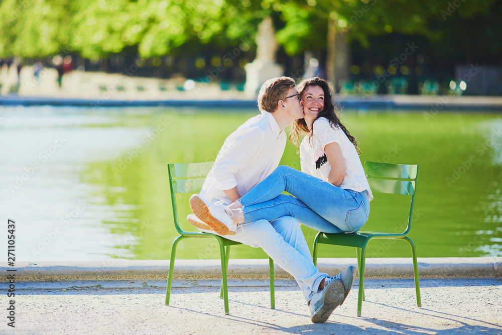 Happy romantic couple in Paris, sitting on traditional green metal chairs in Tuileries garden