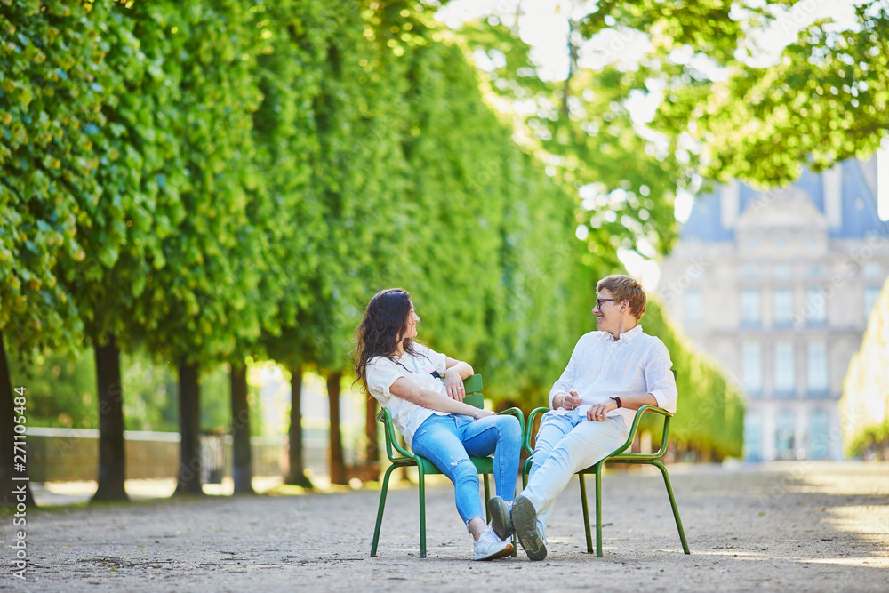 Happy romantic couple in Paris, sitting on traditional green metal chairs in Tuileries garden Happy romantic couple in Paris, sitting on traditional green metal chairs in Tuileries garden