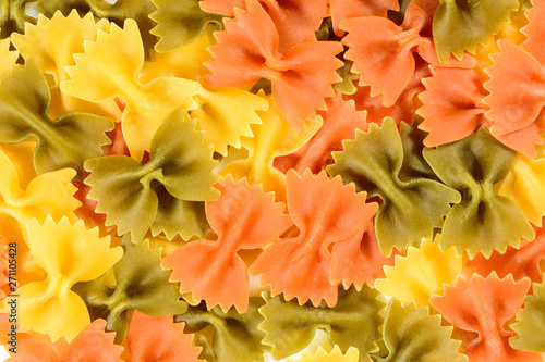 Pasta farfalle, background with traditional colored italian pasta on a brown wooden table. Close up