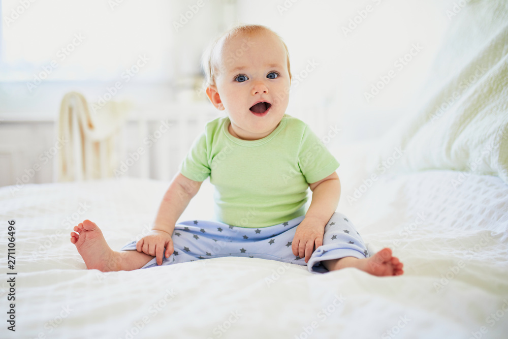 Baby girl sitting on bed and laughing Baby girl sitting on bed and laughing