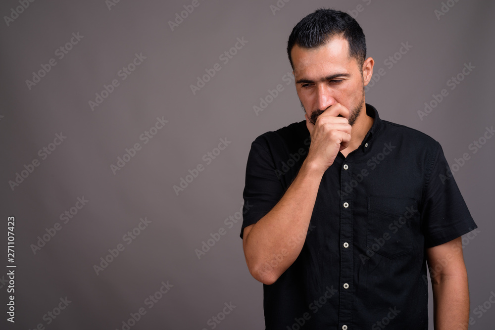 Handsome bearded Persian man against gray background