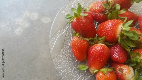 Top view of fresh strawberries in plate on rustic white wood background.