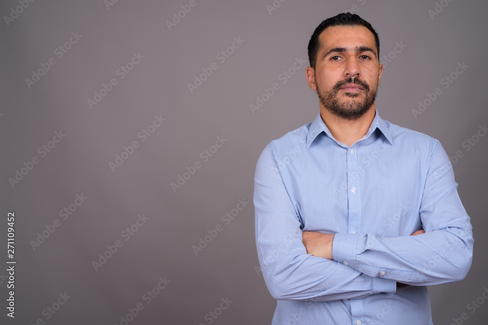 Handsome bearded Persian businessman against gray background Handsome bearded Persian businessman against gray background
