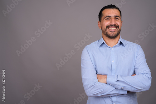 Handsome bearded Persian businessman against gray background
