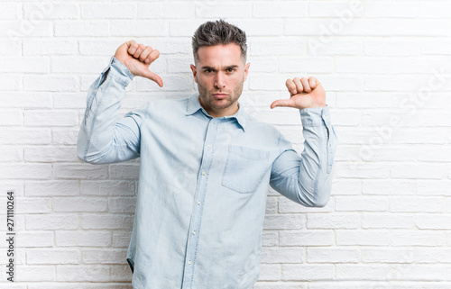 Young handsome man against a bricks wall feels proud and self confident, example to follow.