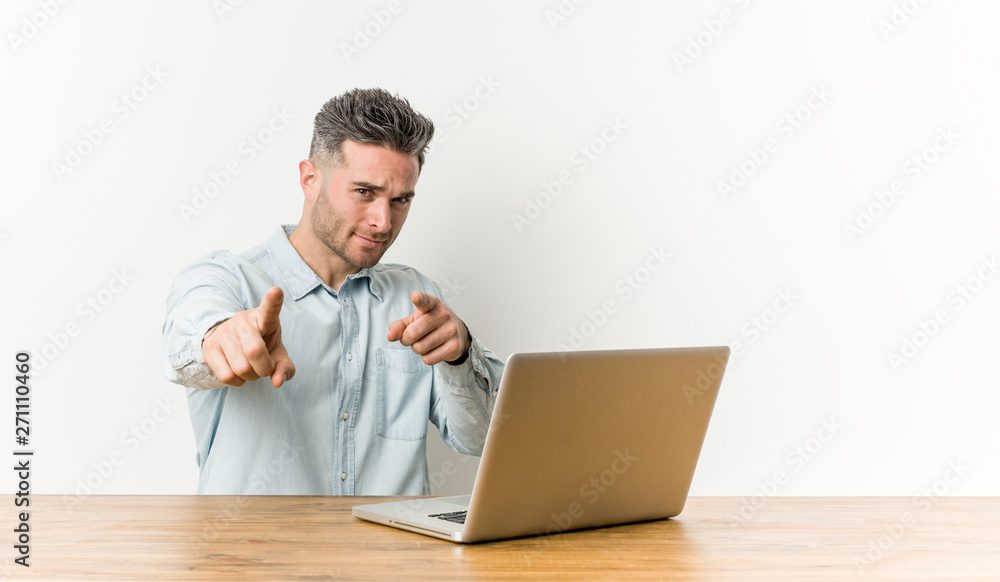 Young handsome man working with his laptop cheerful smiles pointing to front. Young handsome man working with his laptop cheerful smiles pointing to front.