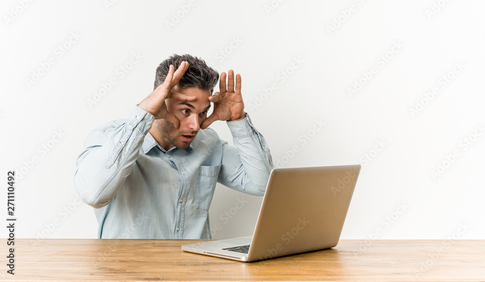 Young handsome man working with his laptop keeping eyes opened to find a success opportunity. Young handsome man working with his laptop keeping eyes opened to find a success opportunity.