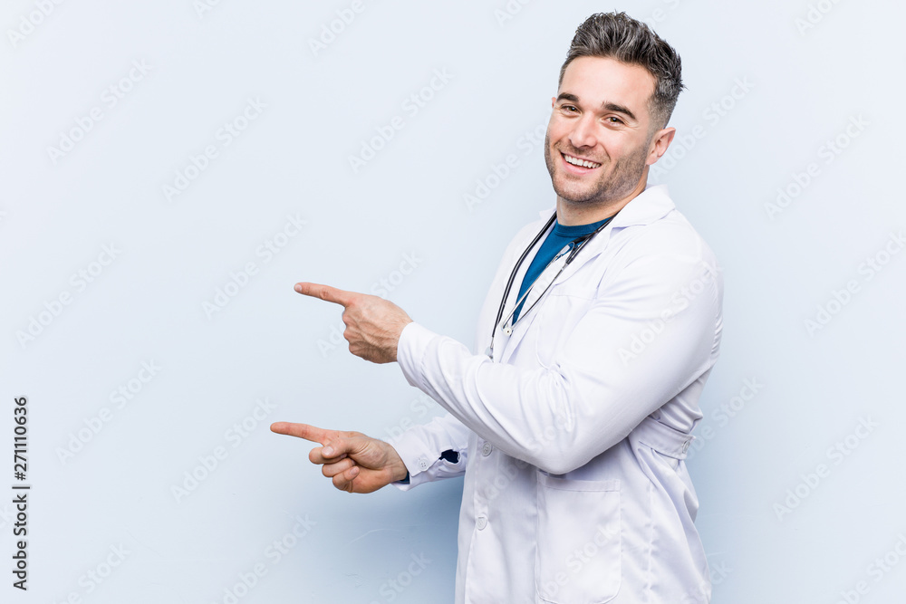 Young handsome doctor man excited pointing with forefingers away. Young handsome doctor man excited pointing with forefingers away.