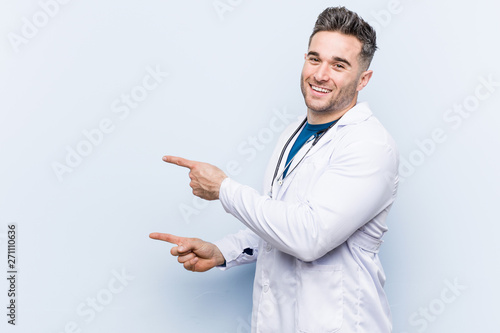 Young handsome doctor man excited pointing with forefingers away.
