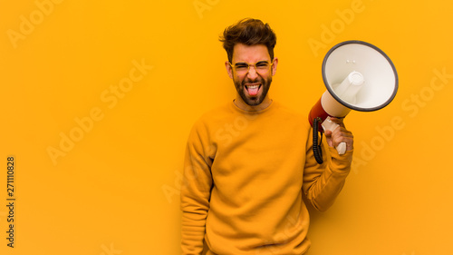 Young man holding a megaphone funnny and friendly showing tongue photo