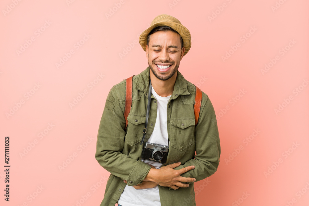 Young filipino traveler man laughs happily and has fun keeping hands on stomach. Young filipino traveler man laughs happily and has fun keeping hands on stomach.