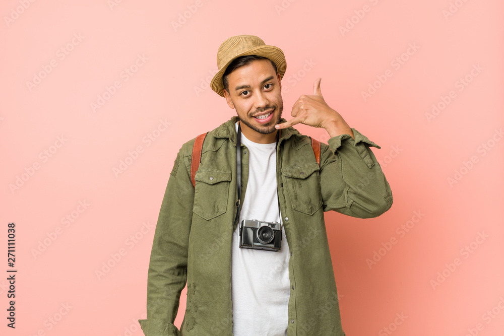 Young filipino traveler man showing a mobile phone call gesture with fingers. Young filipino traveler man showing a mobile phone call gesture with fingers.