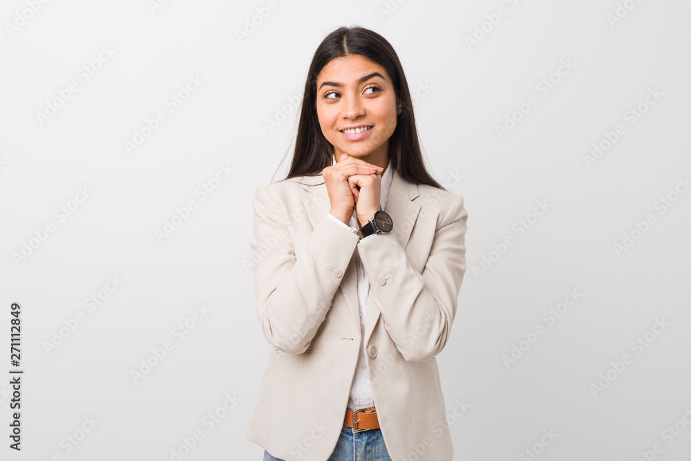 Young business arab woman isolated against a white background keeps hands under chin, is looking happily aside. Young business arab woman isolated against a white background keeps hands under chin, is looking happily aside.