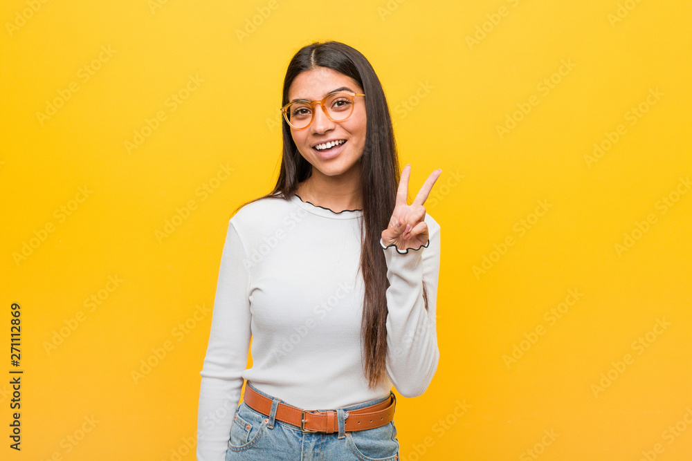 Young pretty arab woman against a yellow background showing victory sign and smiling broadly. Young pretty arab woman against a yellow background showing victory sign and smiling broadly.