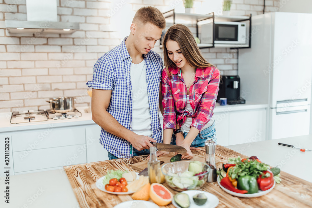 Portrait of a cheerful young couple cooking salad together. Portrait of a cheerful young couple cooking salad together.