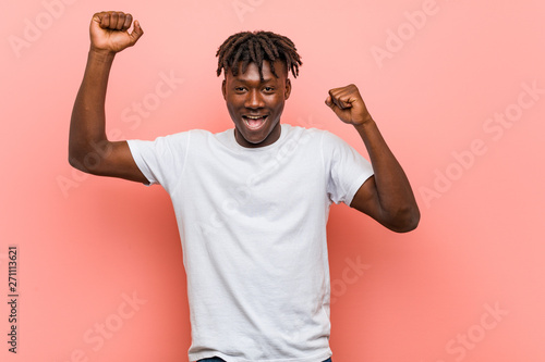 Young african black man celebrating a special day, jumps and raising arms with energy.