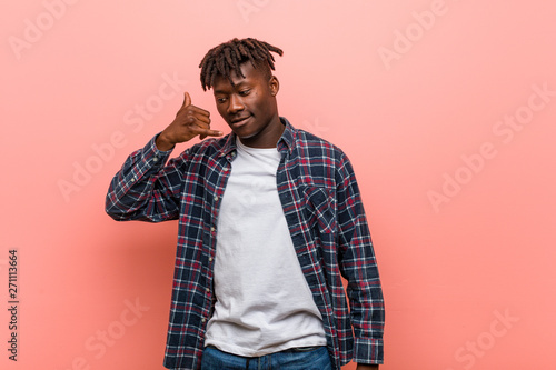 Young african black man showing a mobile phone call gesture with fingers.