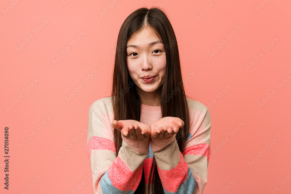 Young cool chinese woman folding lips and holding palms to send air kiss. Young cool chinese woman folding lips and holding palms to send air kiss.