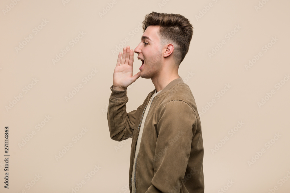 Young caucasian man wearing a brown jacket shouting and holding palm near opened mouth. Young caucasian man wearing a brown jacket shouting and holding palm near opened mouth.