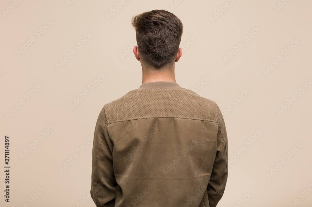 Young caucasian man wearing a brown jacket from behind, looking back. Young caucasian man wearing a brown jacket from behind, looking back.
