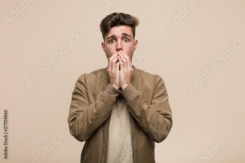 Young caucasian man wearing a brown jacket scared and afraid.