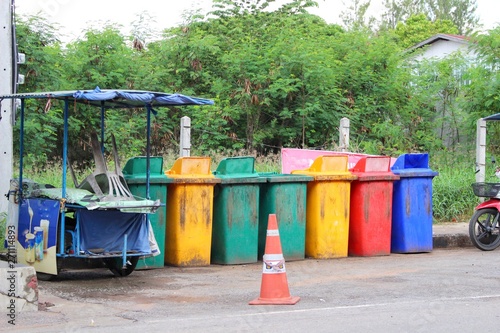 Many colored bins placed in a row beside the road