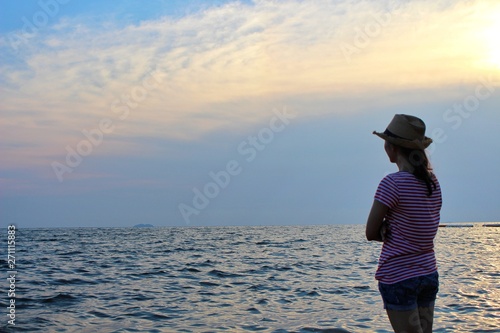  The girl standing on the beach by the sea in the evening